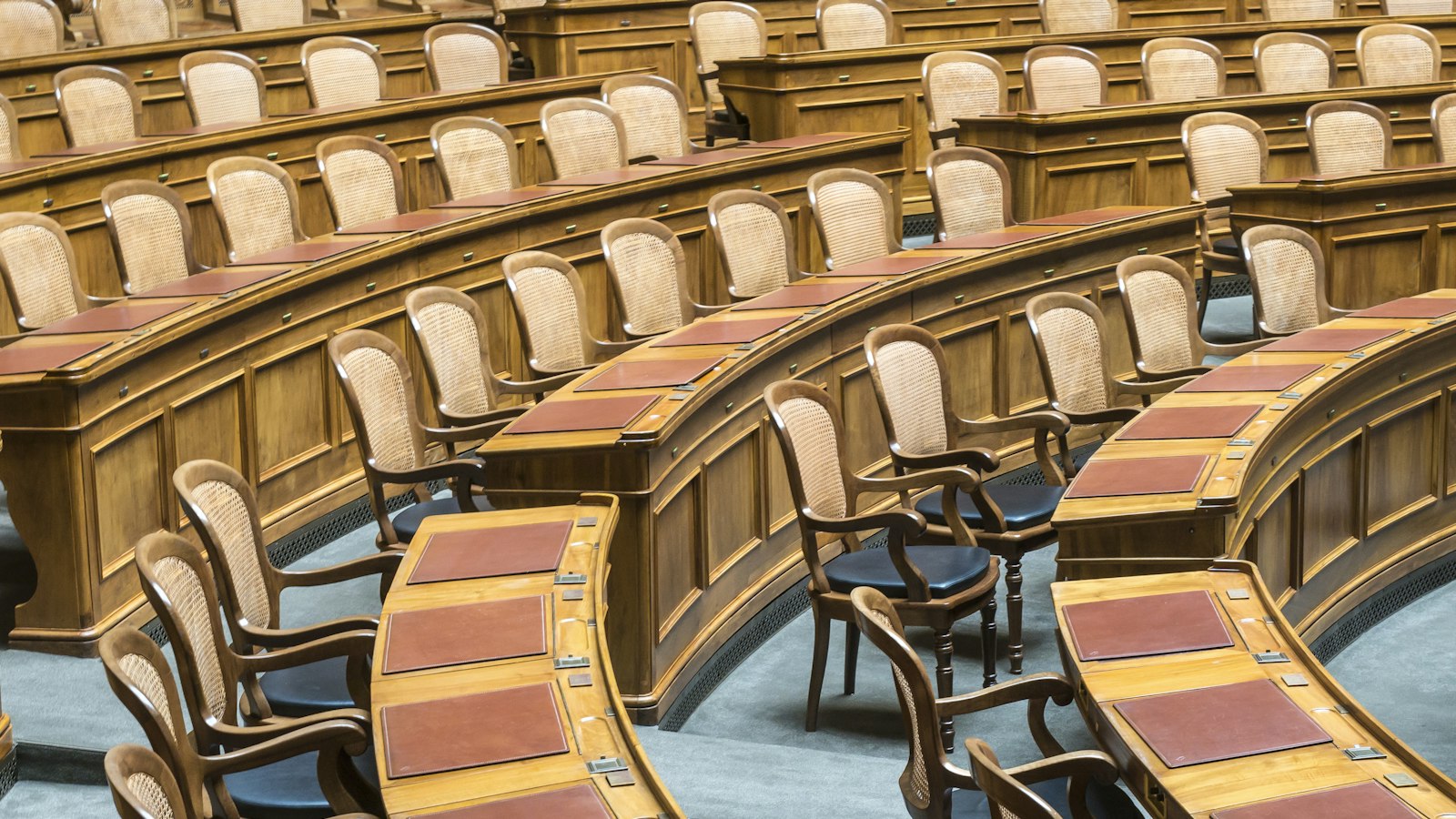 Rangées de sièges en bois dans un hémicycle parlementaire